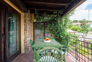 A balcony with a table set for two, a stone wall, and a view of the surrounding area.