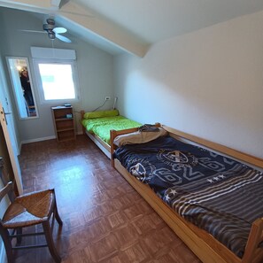 A small, single-room apartment with a bed, a chair, a desk, and a window. - House close to port, air conditioning, bicycles, terrace, parking. (Capbreton)