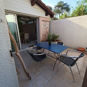 An outdoor patio with a blue table and four chairs, a potted plant, and a stone wall. - House close to port, air conditioning, bicycles, terrace, parking. (Capbreton)
