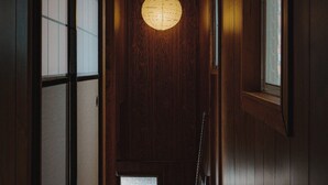 Un couloir aux murs en bois, doté d’un plafond orné de motifs et d’un luminaire circulaire.