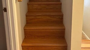Una escalera de madera con barandilla que lleva a un piso superior.