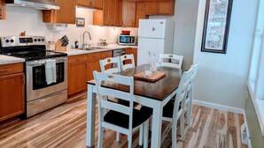Una cocina moderna con armarios de madera, electrodomésticos de acero inoxidable y un comedor con sillas blancas.