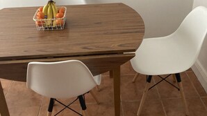 A wooden dining table with a fruit basket, two white chairs, and a white wall. - City Centre Location - Sleeps 6 (Galway)