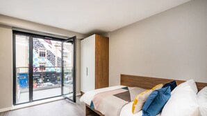 A modern bedroom with a bed, a wardrobe, and a sliding glass door leading to a balcony. - Zinc Works (Bristol)
