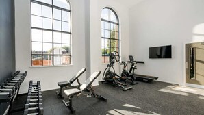 A gym with exercise equipment, large windows, and a flat-screen TV. - Zinc Works (Bristol)