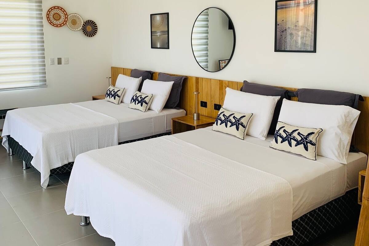A hotel room with two beds, a ceiling fan, an air conditioning unit, and decorative wall art.