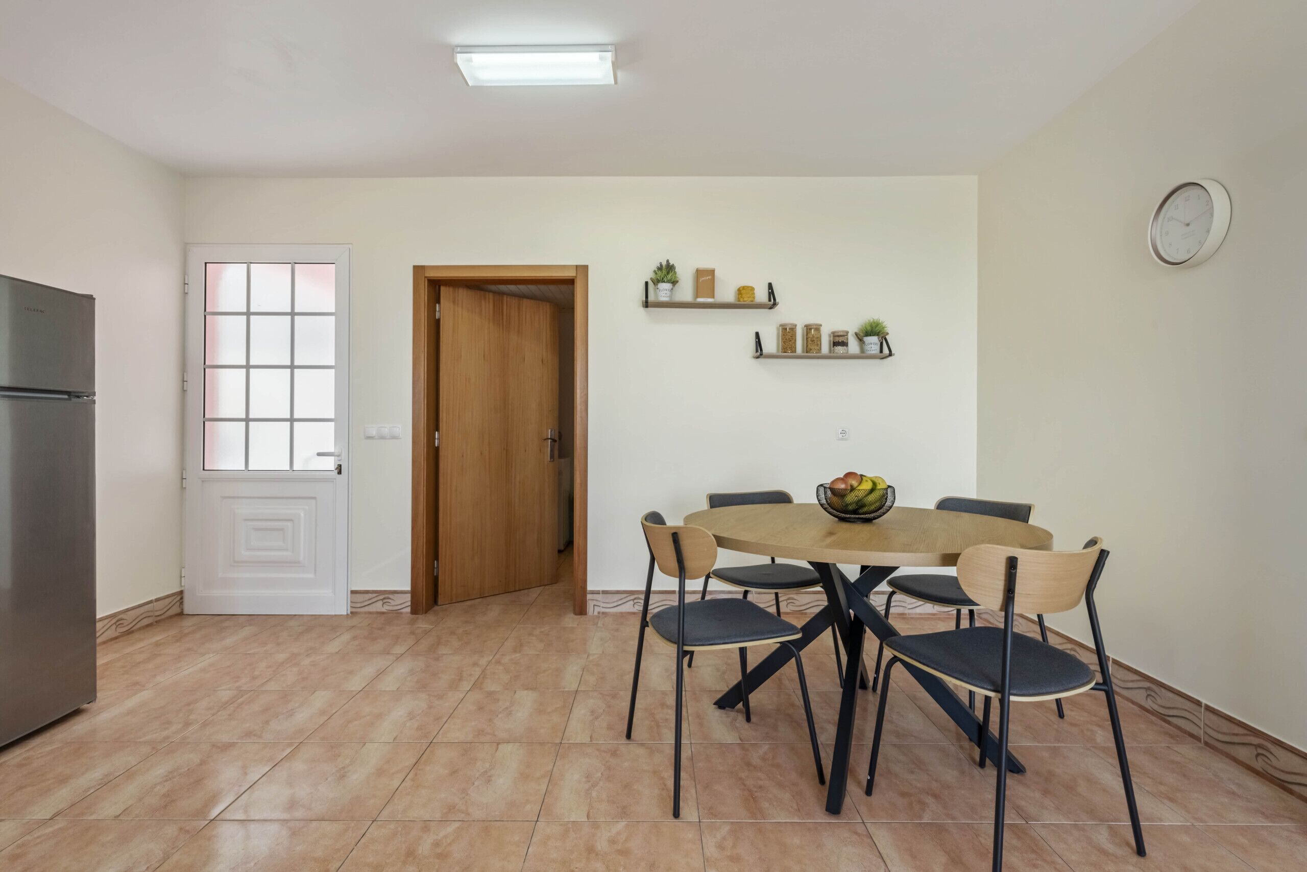 Una cocina con una mesa de comedor, sillas, un refrigerador y una puerta de madera.