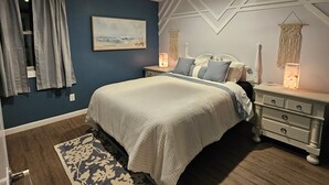 A bedroom with a bed, nightstands, a ceiling fan, a wall-mounted artwork, and a macrame wall hanging. - Cozy Coastal 2-bedroom condo with AC, WiFi in welcoming Saco (Saco)