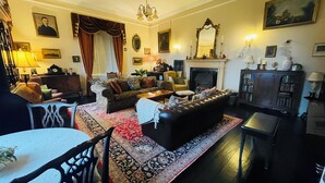 A traditional living room with a fireplace, a sofa set, a dining table, and a chandelier. - Stunning historic manor house with WiFi near charming Nenagh (Nenagh)