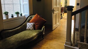 A cozy living room with a green sofa, a wooden staircase, and a view of a hallway. - Stunning historic manor house with WiFi near charming Nenagh (Nenagh)