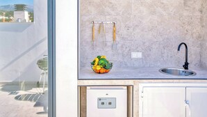 Une cuisine moderne avec un dosseret en marbre, un évier encastré et un panier de fruits posé sur le plan de travail.