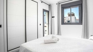 Une chambre d’hôtel moderne avec un grand lit, une armoire et une fenêtre avec des rideaux.