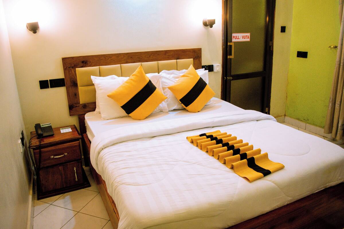 A neatly made bed with a headboard, two pillows, and a folded towel on the bed.