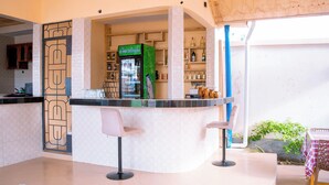 Un espace bar avec un comptoir, des tabourets et un réfrigérateur sur lequel est indiqué : « Boissons fraîches ».