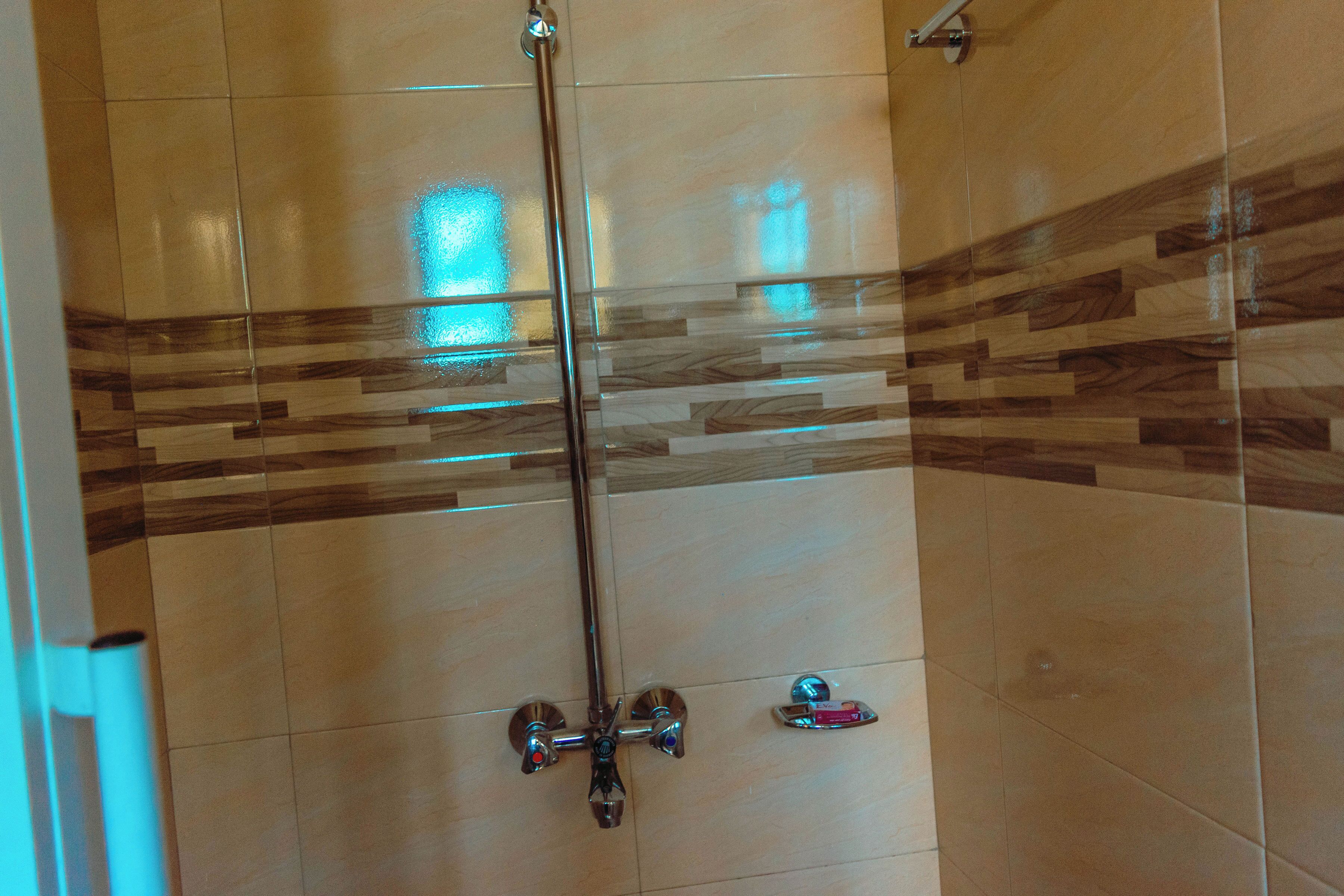 A shower with a glass door and a wooden pattern on the wall.