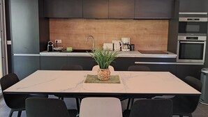 A modern kitchen with dark cabinetry, a marble countertop, and a dining area with a table and chairs. - Hinterland, 35 minutes from Nice, air-conditioned duplex, sleeps 6 from 2 nights (Bouyon)