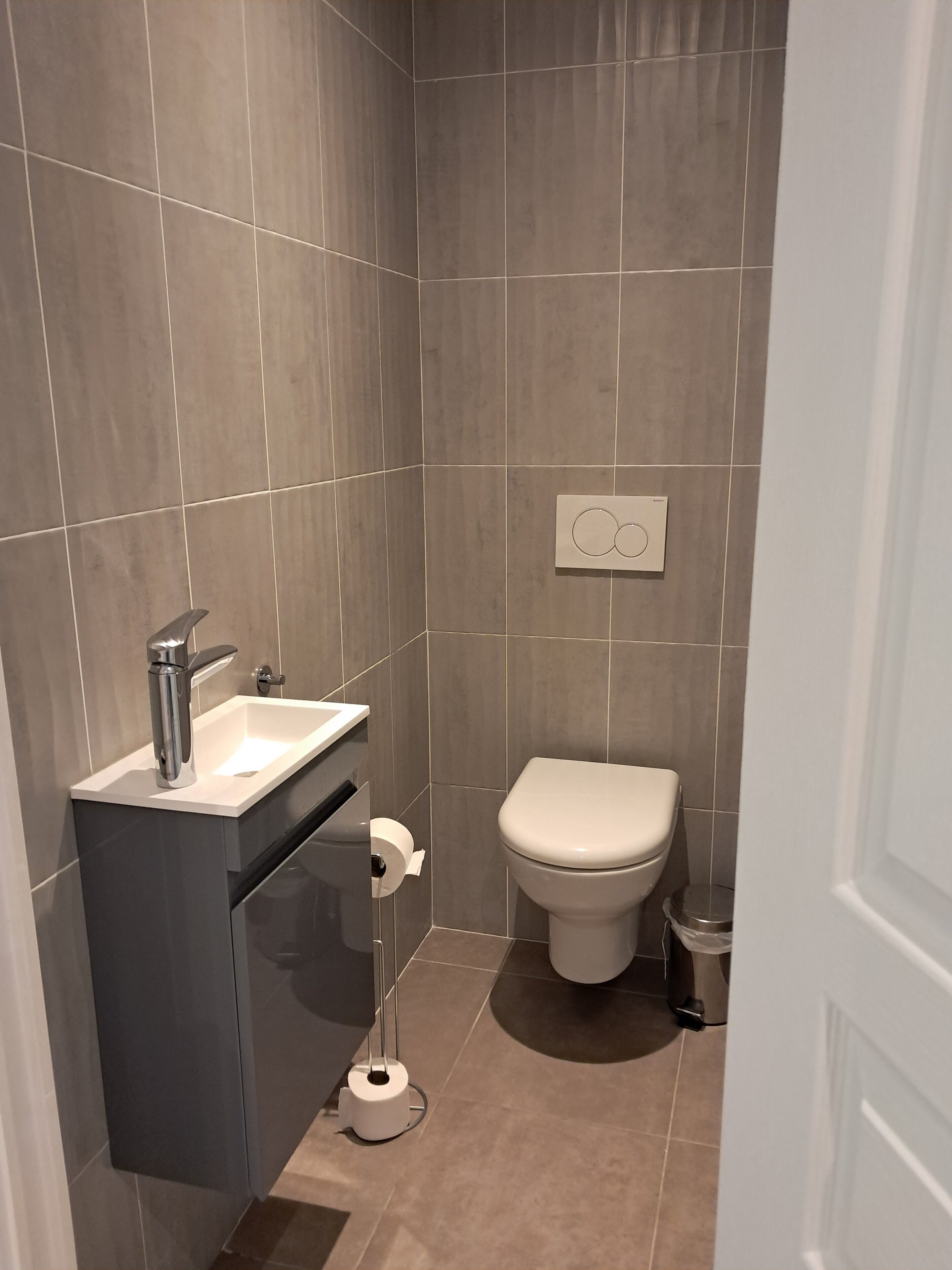 A modern bathroom with a sink, toilet, and a toilet paper holder.