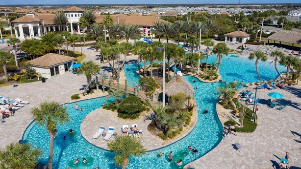 A large outdoor swimming pool with multiple lanes, surrounded by palm trees and lounge chairs.