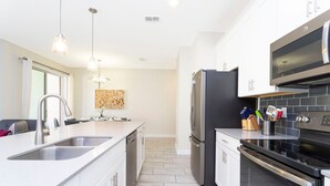 A modern kitchen with white cabinetry, stainless steel appliances, and a tiled backsplash.