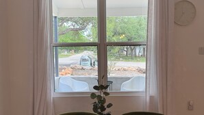 A dining area with a table, chairs, a potted plant, and a view through a window. - Charming 3-bedroom farmhouse in Wimberley with AC, WiFi (Wimberley)