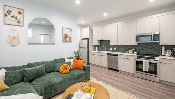 A modern kitchen with light wood cabinets, a microwave, and a built-in oven. - NEW Eco Stay by UChicago, Lakefront & Hyde Park! (Chicago)