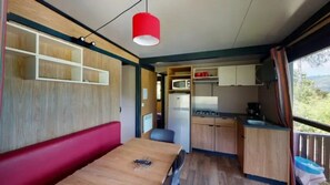 A compact kitchen with wooden cabinets, a refrigerator, and a sink. - ZEcamping 4 étoiles piscine couverte dog friendly animations chalet TV (Vic-sur-Cère)