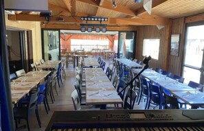 A long dining table with chairs, a keyboard, and a ceiling with lights. - ZEcamping 4 étoiles piscine couverte dog friendly animations chalet TV (Vic-sur-Cère)