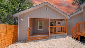A single-story building with a porch, a small window, and a door. - Your Amazing 3BR/2BA Downtown Delight! (San Antonio)