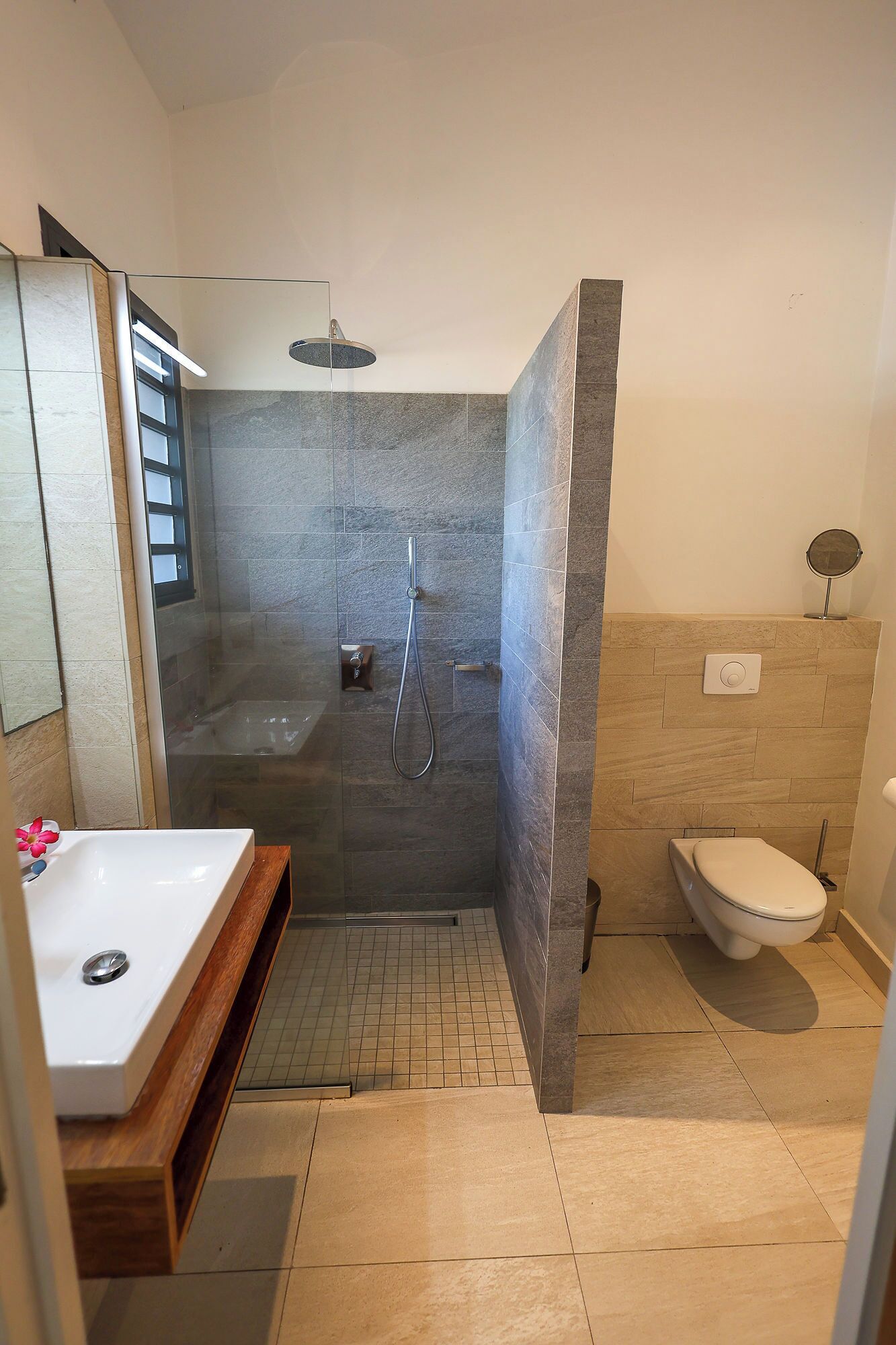 Een moderne badkamer met douche, toilet en wastafel.