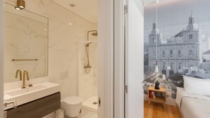 A modern bathroom with a marble wall, a sink with a gold faucet, and a shower.