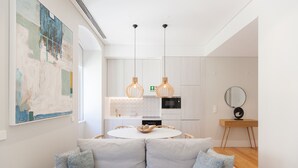 A modern living room with a white sofa, a round dining table, and pendant lights.