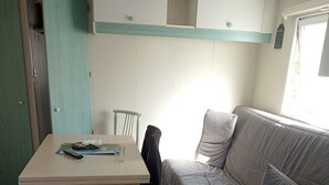 A compact living space with a sofa, a table, and a washing machine. - Mobile home 5/pers, in campsite located in barzan 17kms from Royan with swimming pool. (Barzan)