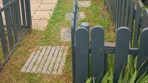 A pathway leading to a row of mobile homes with a wooden fence on one side and a metal gate on the other. - Mobile home 5/pers, in campsite located in barzan 17kms from Royan with swimming pool. (Barzan)
