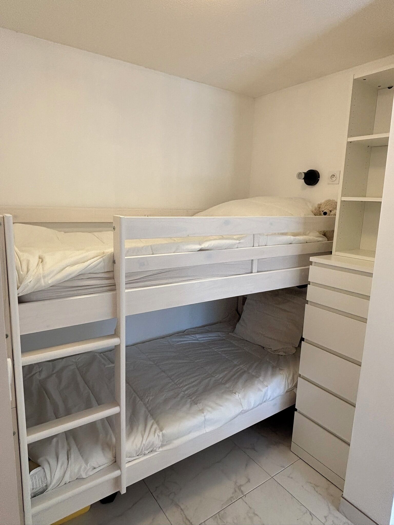 Ein Etagenbett mit unterer Ablage und ein Kleiderschrank mit mehreren Schubladen.