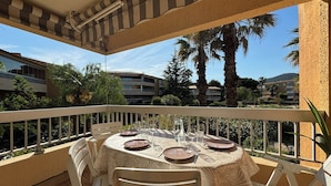 Ein Balkon mit rundem Tisch für zwei Personen, umgeben von weißen Stühlen.