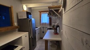 Una cocina compacta con refrigerador, lavamanos y encimera de madera.