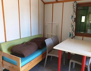 A room with a wooden bed, a table, and a chair. - ZEcamping familial pataugeoire pet friendly chalet TV 2 pers (Argentonnay)