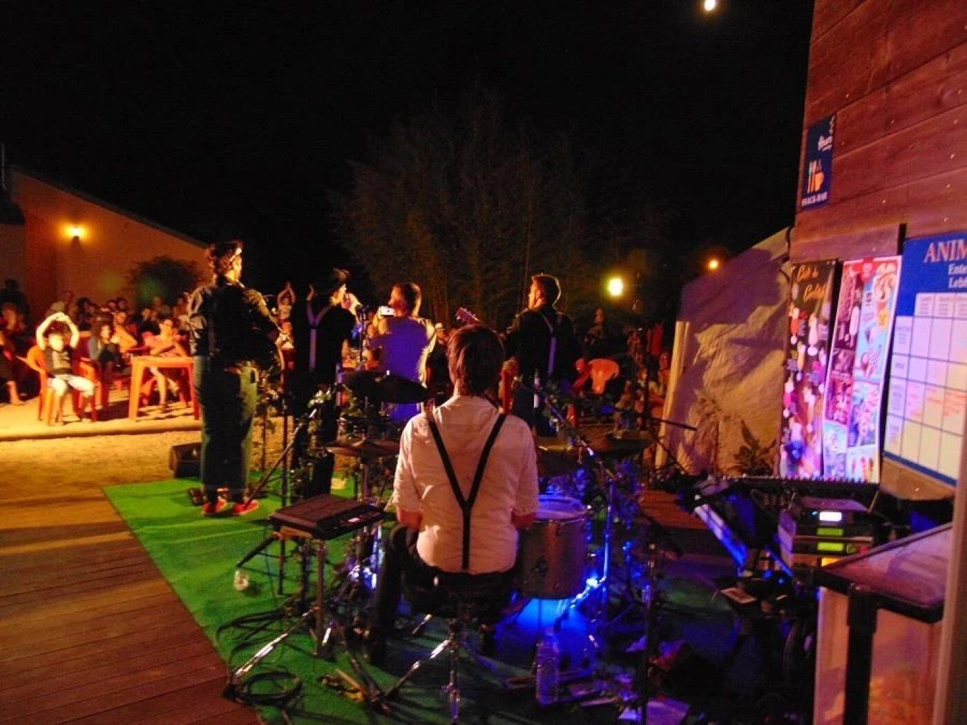Um palco ao ar livre com instrumentos musicais e uma multidão de pessoas.