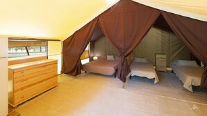 A tented accommodation with two beds, a wooden dresser, and a window. - ZEcamping 2 étoiles piscine animaux acceptés locatif 4 pers (Ghisonaccia)