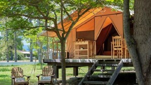 A treehouse with a wooden deck, a ladder, and two chairs. - ZEcamping 2 étoiles piscine animaux acceptés locatif 4 pers (Ghisonaccia)