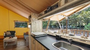 Eine kleine Küche mit Spüle, Holzschränken und einem Fenster mit Blick auf eine Terrasse.