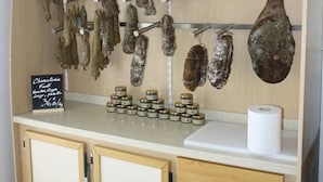 A charcuterie display with hanging cured meats and jars of preserves.
