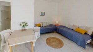 A compact living space with a dining table, two sofas, a small rug, and a single lamp. - ZEcamping 2* piscine accès direct plage locatif 4 pers (Ghisonaccia)