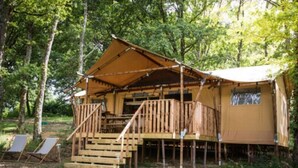 A wooden cabin with a balcony, surrounded by trees.