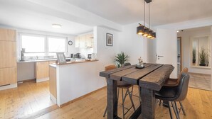 Eine moderne Küche mit Holzschränken, einer zentralen Kochinsel und einem Essbereich mit rustikalem Holztisch und -stühlen.