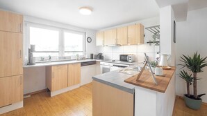 Eine moderne Küche mit Holzschränken, einem großen Fenster und einem Blumentopf.