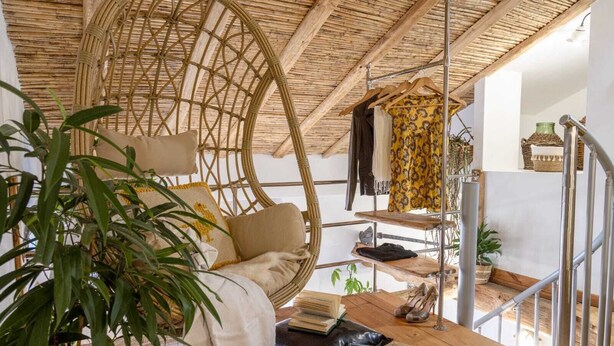 A room with a hanging chair, a wooden shelf with clothes, a staircase, and a plant. - 900 mt from the historic center of Tortolì and 5 km from all the most beautiful beaches. (Tortolì)