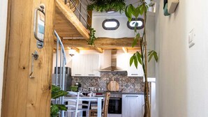 A kitchen with white cabinets, a dining table with chairs, and a hanging plant. - 900 mt from the historic center of Tortolì and 5 km from all the most beautiful beaches. (Tortolì)