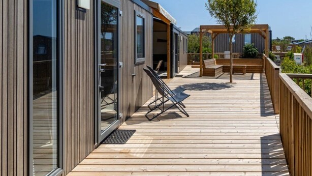 A modern building with large glass doors, a wooden deck, and outdoor seating. - ZEcamping 3 étoiles piscine chauffée dog friendly locatif TV LV BBQ (Martigues)