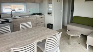 A modern kitchen with a dining area, a sofa, and a small table. - ZEcamping 3 étoiles piscine chauffée dog friendly locatif TV LV BBQ (Martigues)